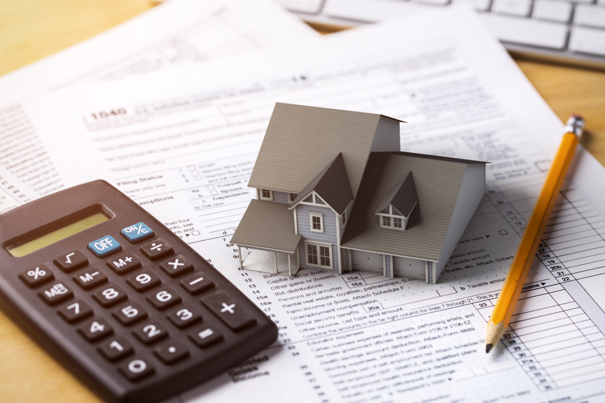 Tax papers with a calculator and model house