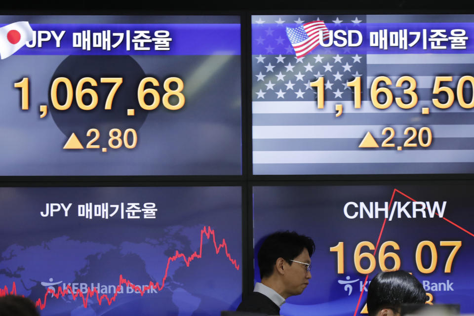 A currency trader walks past in front of the screens showing the foreign exchange rates at the foreign exchange dealing room in Seoul, South Korea, Wednesday, Nov. 13, 2019. Asian stocks sank Wednesday after U.S. President Donald Trump threatened more tariff hikes on Chinese imports if talks aimed at ending a trade war fail to produce an interim agreement. (AP Photo/Lee Jin-man)