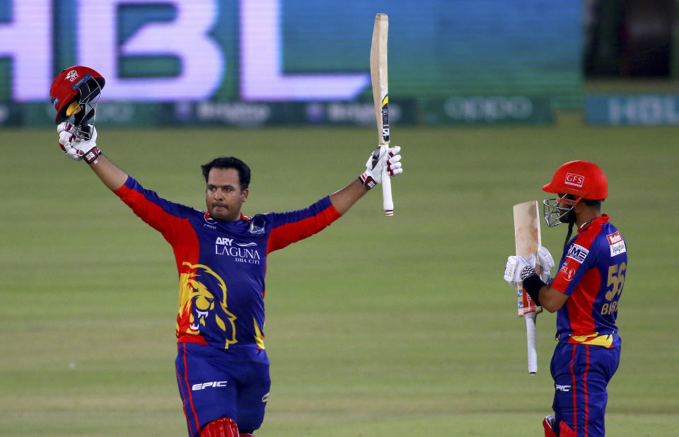 Karachi Kings' Sharjeel Khan, left, raises his bat and helmet to celebrate after scoring century while teammate Babar Azam watches during a Pakistan Super League T20 cricket match between Karachi Kings and Islamabad United at the National Stadium, in Karachi, Pakistan, Wednesday, Feb. 24, 2021. (AP Photo/Fareed Khan)