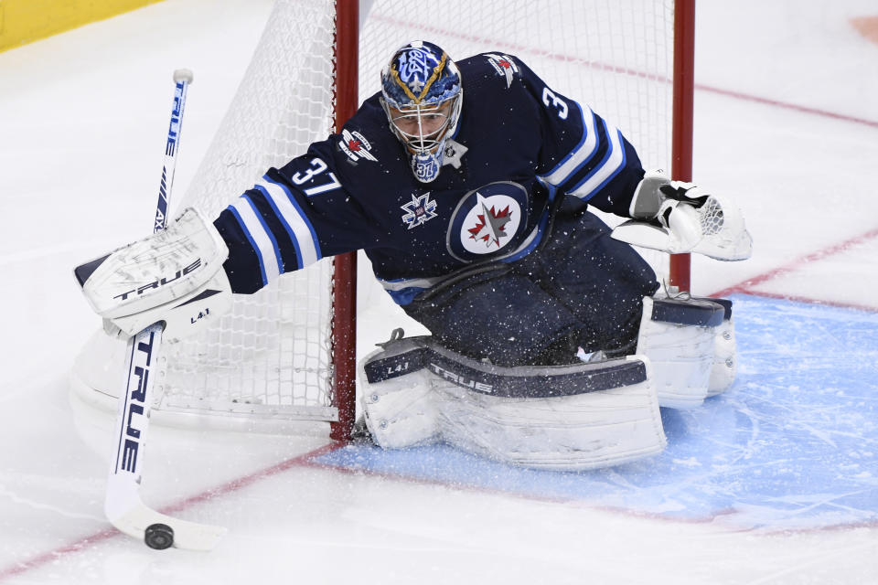 Winnipeg Jets goaltender Connor Hellebuyck steers a shot by the Edmonton Oilers to the corner during the second period of an NHL hockey game Tuesday, Jan. 26, 2021, in Winnipeg, Manitoba. (Fred Greenslade/The Canadian Press via AP)