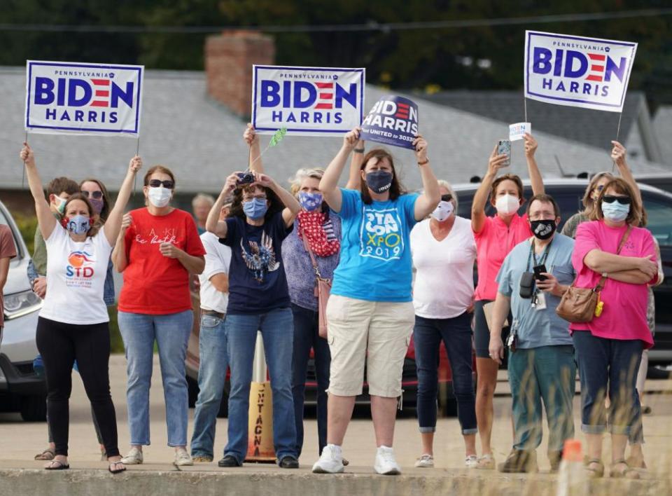 Supporters hold signs as they await the arrival of Joe Biden in Erie, Pennsylvania, on 10 October.