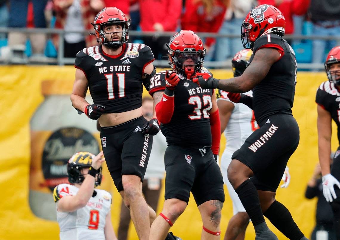 N.C. State linebacker Isaiah Moore (1) celebrates with linebacker Drake Thomas (32) after Thomas sacked Maryland quarterback Billy Edwards Jr. (9) during the first half of N.C. State’s game against Maryland in the Duke’s Mayo Bowl at Bank of America Stadium in Charlotte, N.C., Friday, Dec. 30, 2022. N.C. State linebacker Payton Wilson (11) is to the left.