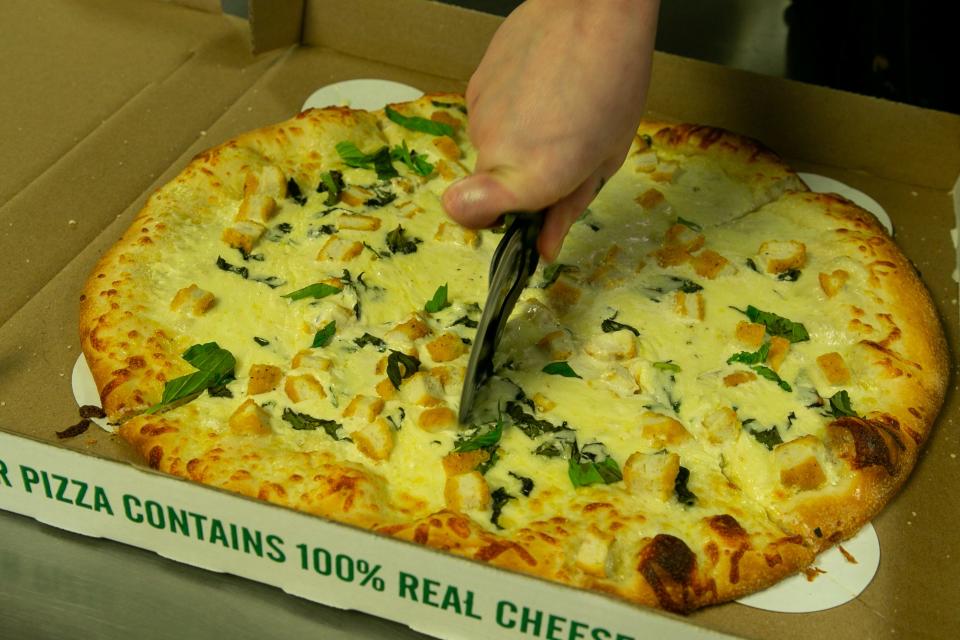 Kylie Painter, a pizzaiolo at Authentic New York Pizza, slices up a chicken Alfredo pizza on Wednesday, Feb. 8, 2023.