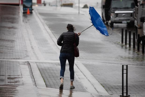 A pedestrian's umbrella is blown inside-out during a rainstorm in Vancouver, B.C. on Friday, Sept. 17, 2021. (Maggie MacPherson/CBC - image credit)