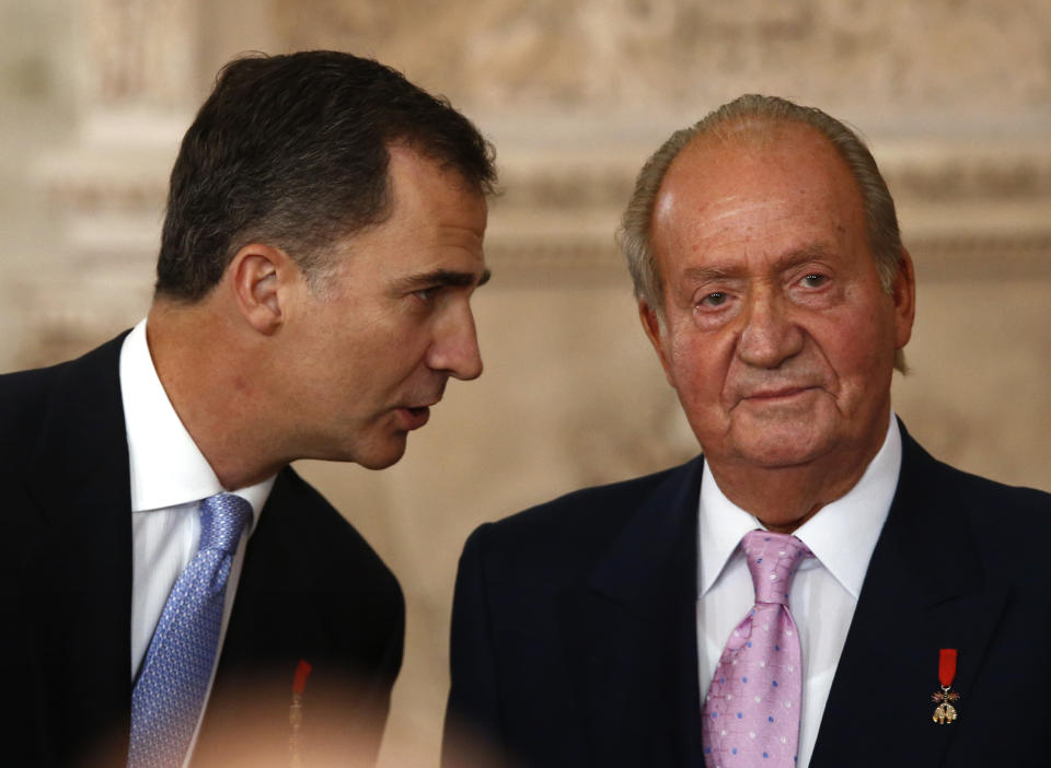 FILE - In this Wednesday June 18, 2014 file photo, Spanish Crown Prince Felipe, left speaks with Spanish King Juan Carlos after he signed an abdication law during a ceremony at the Royal Palace in Madrid, Spain. Former Spanish King Juan Carlos I has paid close to 4.4 million euros ($5.33 million) in a debt with the country’s tax authorities it was announced Friday, Feb. 26, 2021, his latest attempt to regularize past undeclared income. The former monarch has been living abroad for more than half a year after media revealed fresh allegations of financial misdoings. (AP Photo/Daniel Ochoa de Olza)