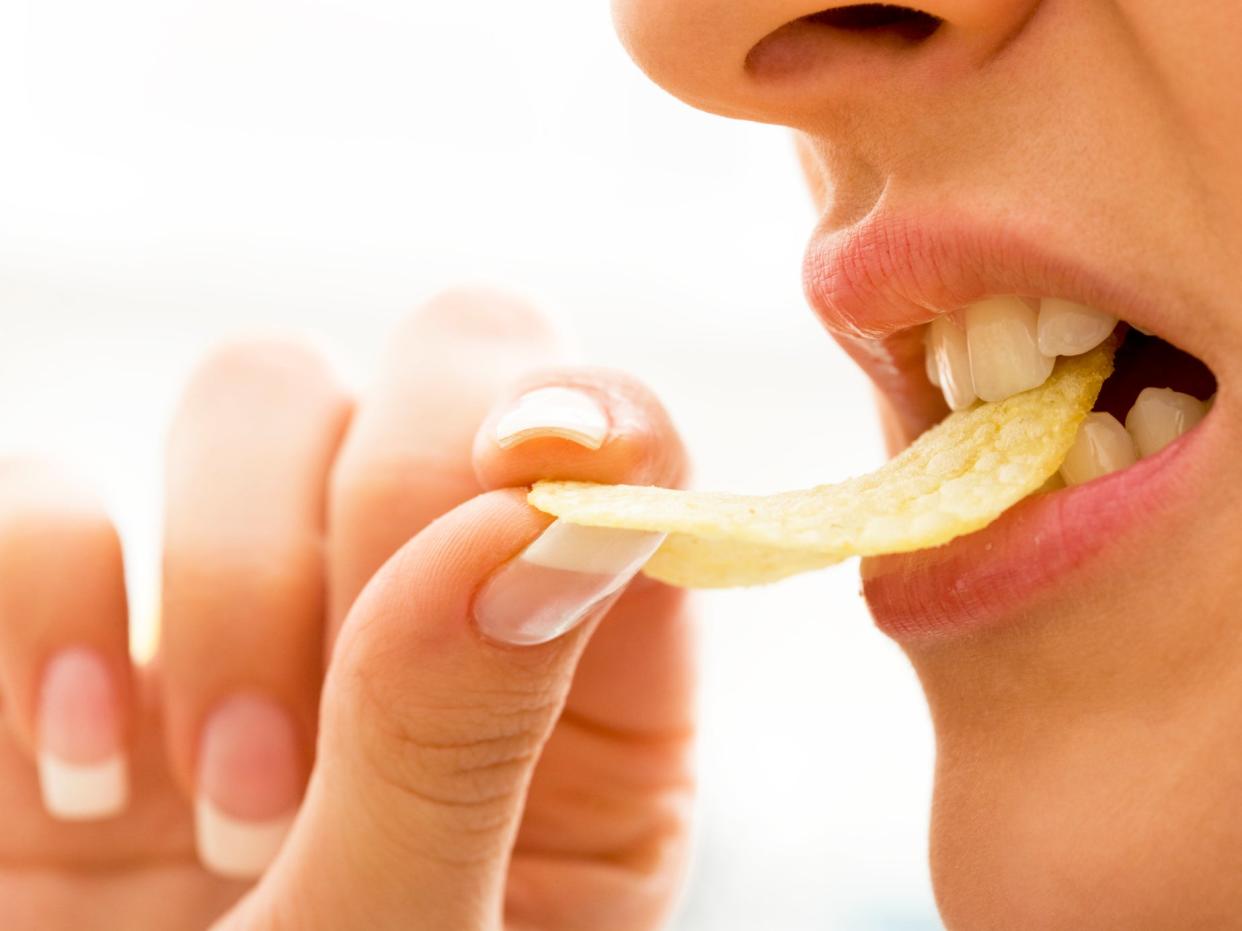 A person takes a bite of a crisp (Getty Images/iStockphoto)