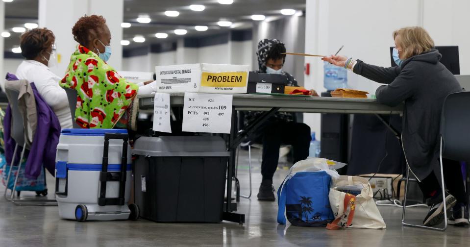 An election worker passes an absentee ballot down the line during the counting and tabulation of ballots from a few of Detroit's 450 precincts inside in Hall E at Huntington Place in Detroit on Tuesday, August 2, 2022. 