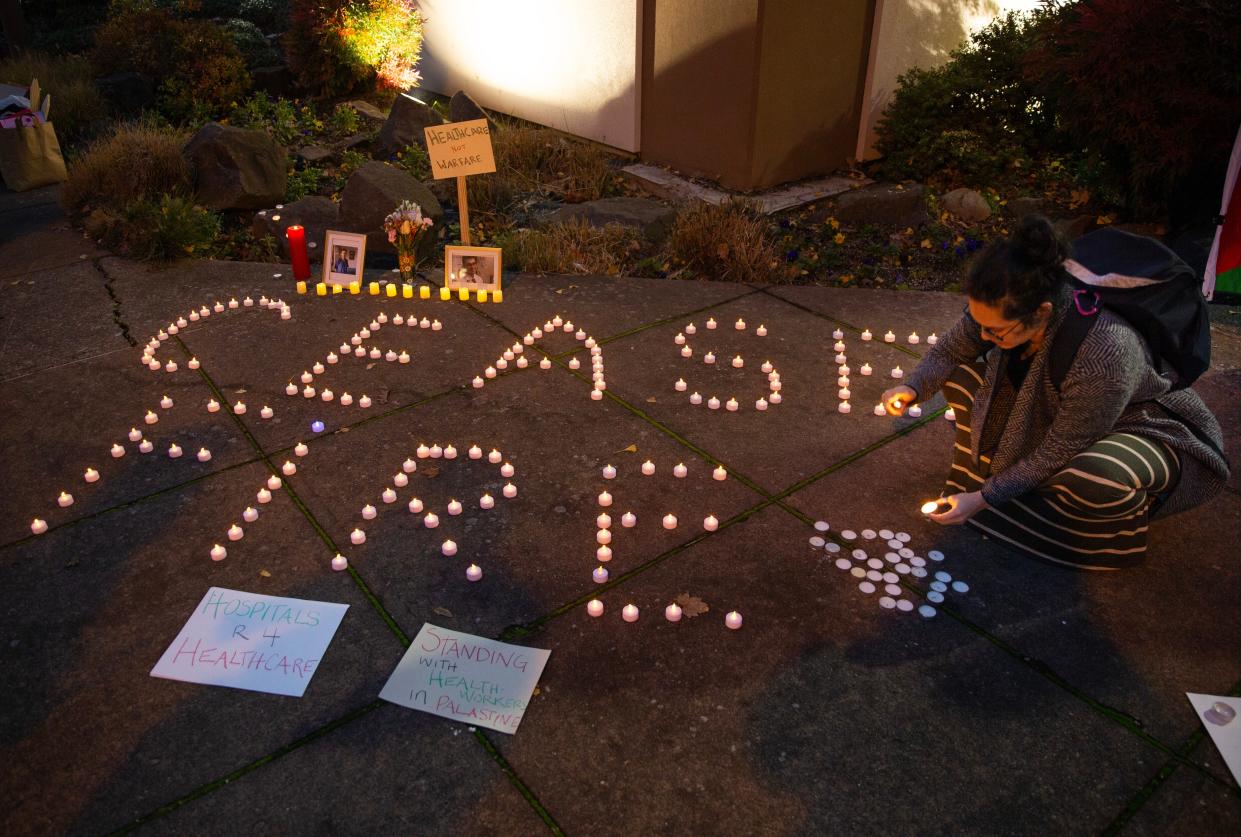 Aya Cockram, right, lights candles during a vigil for healthcare workers in Gaza. About 80 local doctors, nurses and supporters gathered at 13th and Hilyard in Eugene calling for a cease fire in the region.