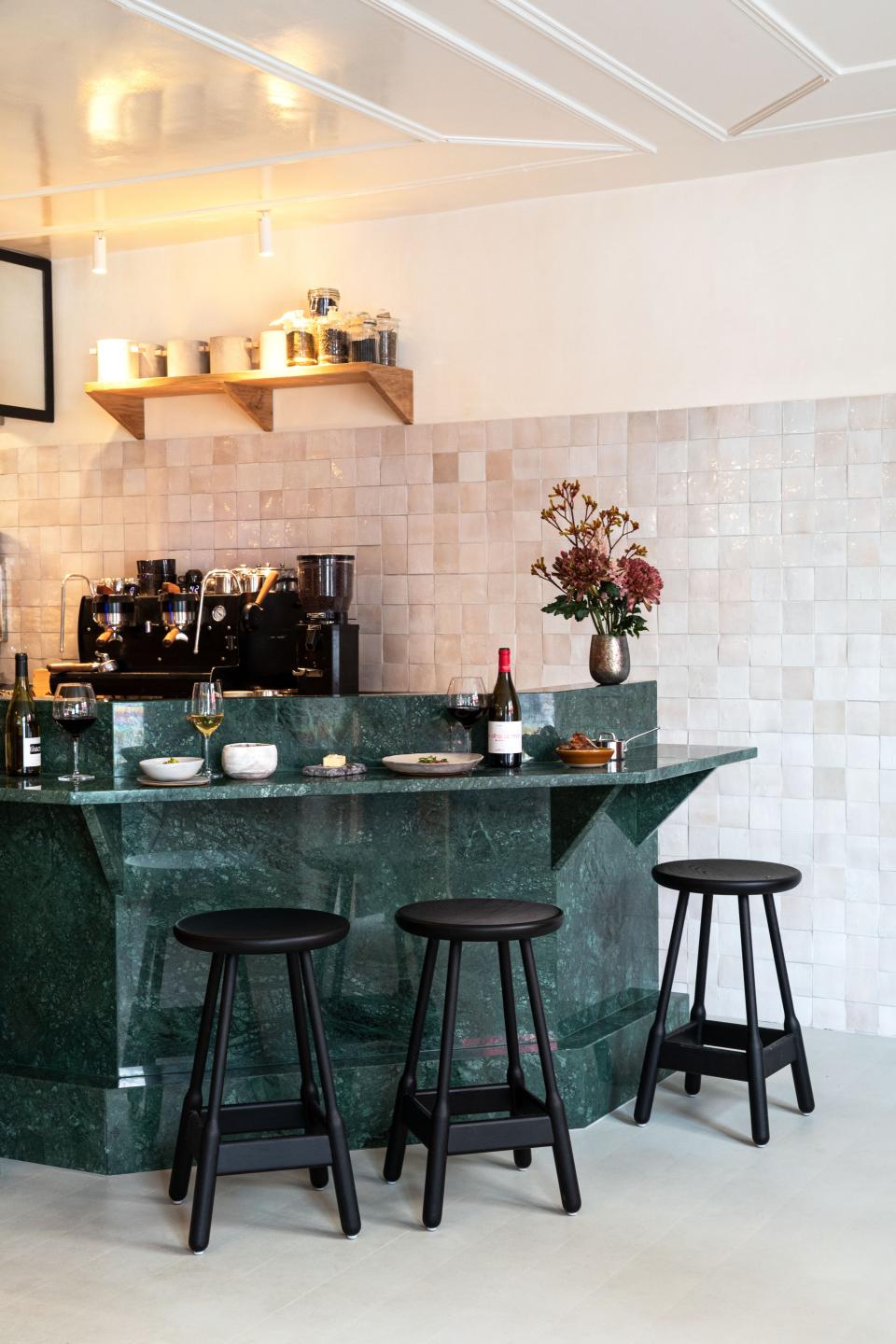 The rich green marble bar makes a great contrast against the pale square tilework along the wall.