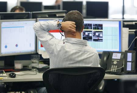 FILE PHOTO: A trader sits at his desk at IG Index in London September 9, 2014. Britain's top shares fell on Tuesday as weaker energy stocks weighed, extending the previous day's retreat on concerns that Scotland could vote to leave the United Kingdom. REUTERS/Luke MacGregor