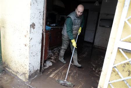 A man sweeps muddy water out of his flooded home following extreme rainfall in Olbia on Sardinia island November 20, 2013. REUTERS/Tony Gentile