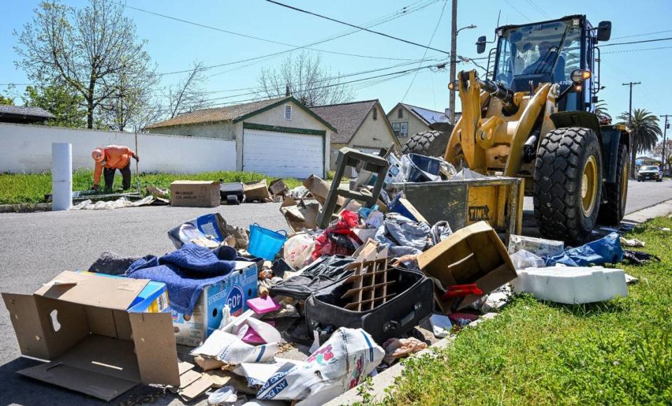 Un trabajador de la ciudad utiliza "la garra" cargador frontal para recoger la basura residencial dejado fuera en una calle en el sureste de Fresno durante la Operación Limpieza en Fresno el lunes, 8 de abril 2024. CRAIG KOHLRUSS/ckohlruss@fresnobee.com