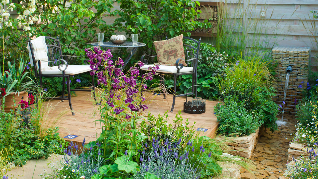 Relaxing area in garden with decking and setting among plants. 