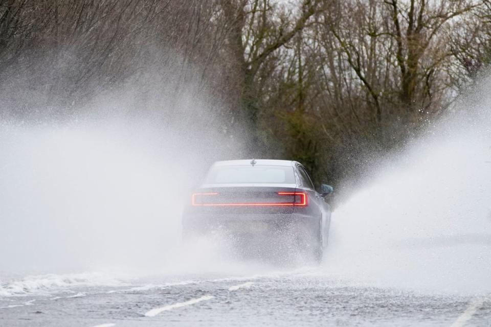 Cars make their way through surface water on the A1101 in Welney in Norfolk on 7 December 2023 (PA)