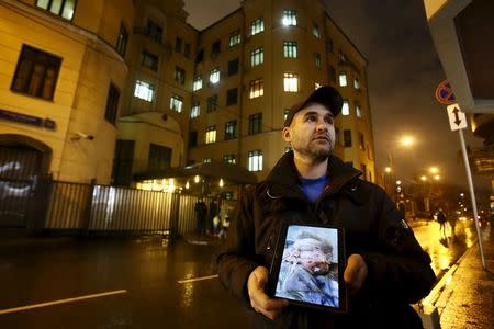 An activist holds a tablet with a picture of the lifeless body of a Russian pilot of a war plane shot down by Turkey, in front of the Turkish embassy in Moscow, Russia, November 24, 2015. REUTERS/Maxim Shemetov