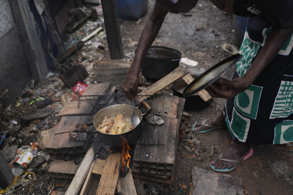 Lady Laurentino, 74, cooks in a wood fire near the door of her home in the Jardim Gramacho favela of Rio de Janeiro, Brazil, Monday, Oct. 4, 2021. With the surge in cooking gas prices, Laurentino says she is cooking with wood because she doesn't have money to buy another cooking gas cylinder. (AP Photo/Silvia Izquierdo)