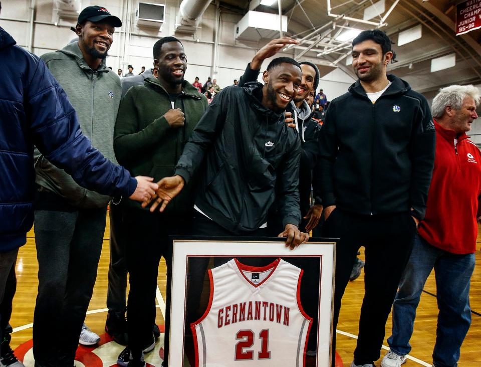  NBA player Ian Clark (middle) is surrounded by Golden State Warriors teammates including Kevin Durant (left) and Draymond Green (second left) as his Germantown High School basketball jersey was retired during a ceremony Friday night.