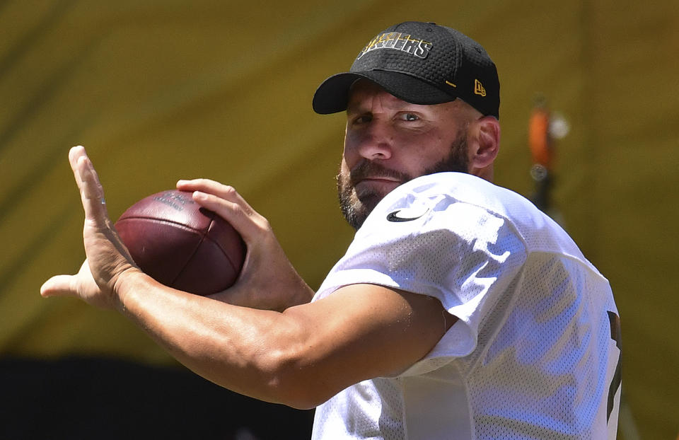 Ben Roethlisberger drops back to pass wearing a white jersey and black ballcap.