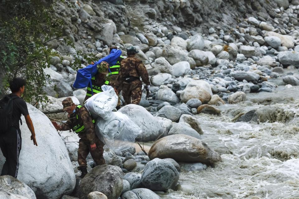 In this photo released by Xinhua News Agency, rescuers deliver supplies via an uphill path in the aftermath of an earthquake along the Moxi River near Moxi Town of Luding County, southwest China's Sichuan Province, Sept. 8, 2022. Heavy rains are complicating earthquake recovery efforts in southwestern China, where the death toll from Monday's disaster has risen. (Shen Bohan/Xinhua via AP)