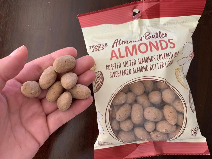 hand holding trader joe&#39;s almond butter almonds beside white and red bag