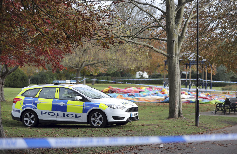 Police cordon off the deflated inflatable slide, at rear, in Woking Park, south England, Saturday Nov. 3, 2018. British police say seven of the eight children hurt when they fell from an inflatable slide at a fair in southern England have been discharged from the hospital. (Andrew Matthews/PA via AP)