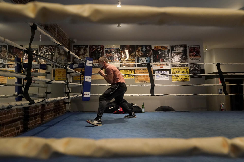 Leo Larsen wears a mask while shadow boxing in the ring before instructing a class at a Hit Fit SF gym amid the coronavirus outbreak in San Francisco, Tuesday, Nov. 24, 2020. (AP Photo/Jeff Chiu)