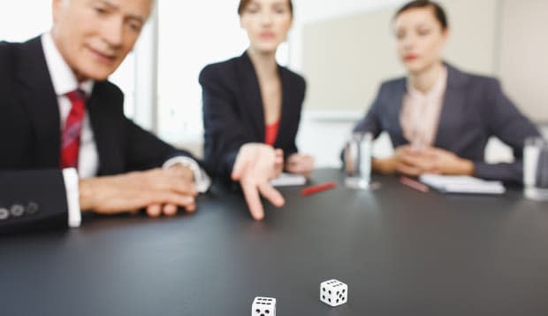 Business people throwing dice on conference room table