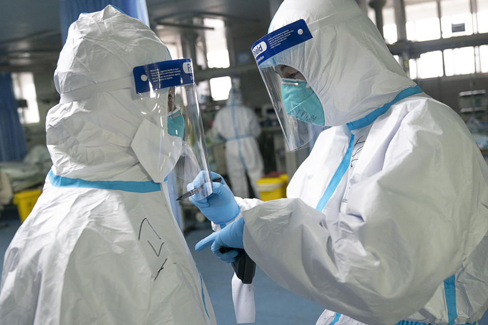 In this photo released by China's Xinhua News Agency, a medical worker writes their colleague's name on a protective suit to aid in identification as they work at Zhongnan Hospital of Wuhan University in Wuhan in central China's Hubei Province, Firday, Jan. 24, 2020. China announced Friday that it is swiftly building a 1,000-bed hospital dedicated to patients infected with a new virus that has killed 26 people, sickened hundreds and prompted unprecedented lockdowns of cities during the country's most important holiday. (Xiong Qi/Xinhua via AP)