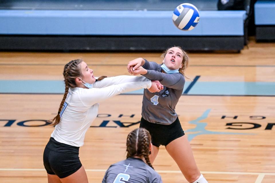 Lansing Catholic's Isabella Schultz, left, and Cady Kooney close in on the ball during the volleyball match against Ionia on Monday, Sept. 20, 2021, at Lansing Catholic High School. The Cougars won the match 3 sets to 1.