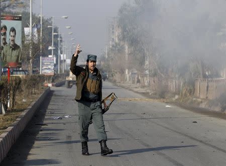 An Afghan policeman reacts as smoke billows during an attack near the Pakistani consulate in Jalalabad, Afghanistan January 13, 2016. REUTERS/ Parwiz