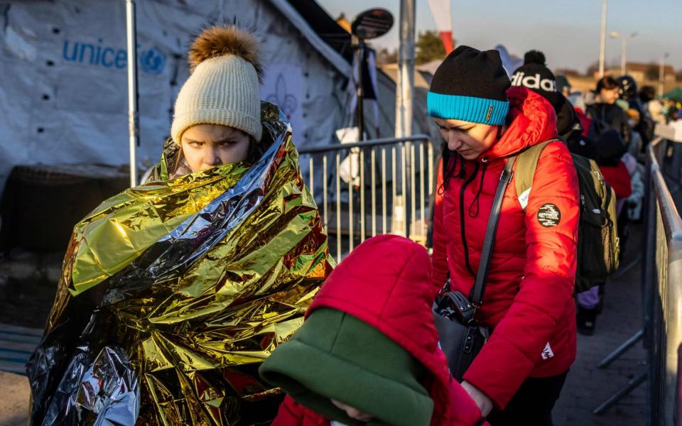 A girl is wrapped in a rescue blanket as she and others line up to get on to the buses  - Wojtek Radwanski/AFP 