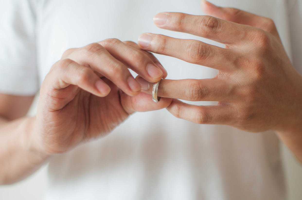 A close-up view of a young man's hands removing his wedding ring a concept of relationship difficulties divorce