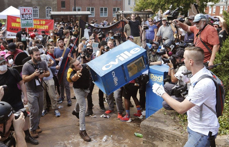 White nationalist demonstrators clash with a counter demonstrator as he throws a newspaper box at the entrance to Lee Park in Charlottesville, Va., Saturday, Aug. 12, 2017. Gov. Terry McAuliffe declared a state of emergency and police dressed in riot gear ordered people to disperse after chaotic violent clashes between white nationalists and counter protestors. (AP Photo/Steve Helber) (AP Photo/Steve Helber)