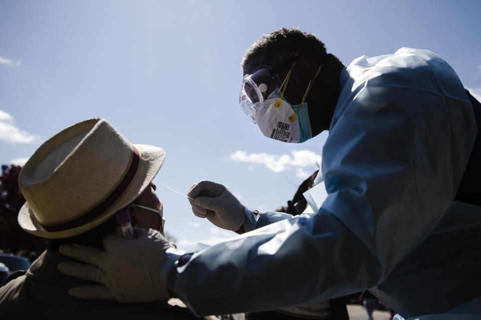 Dr. Pierre Chanoine administers a COVID-19 swab test on a person outside the of the Pinn Memorial Baptist Church in Philadelphia, Wednesday, April 22, 2020. The Black Doctors COVID-19 Consortium offers testing at various locations to help address heath disparities in African American neighborhoods. (AP Photo/Matt Rourke)