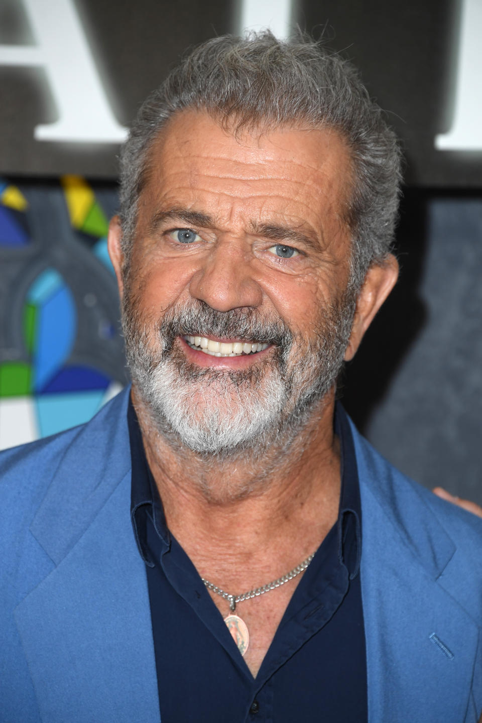 Close-up of Mel smiling with salt-and-pepper hair, mustache, and beard