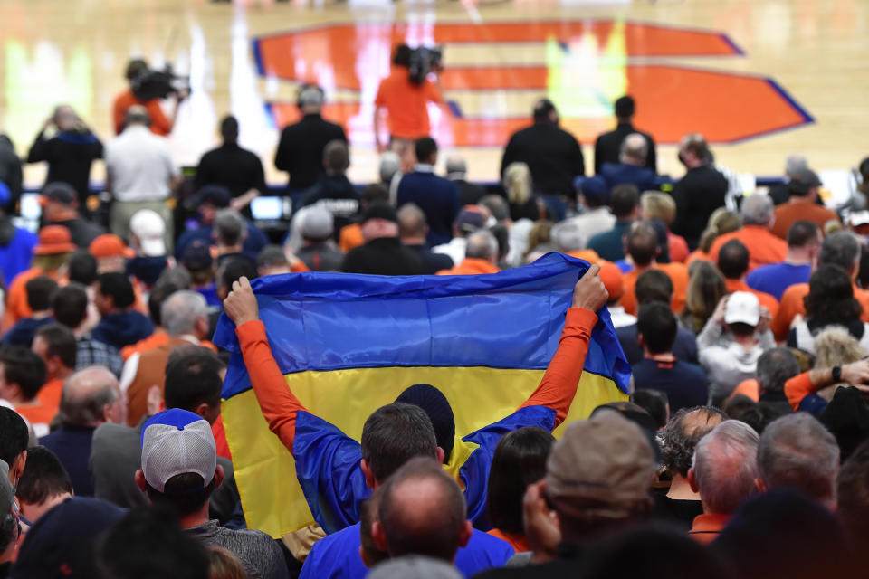 A fan holds a Ukrainian flag during a moment of silence before an NCAA college basketball game between Syracuse and Duke in Syracuse, N.Y., Saturday, Feb. 26, 2022. (AP Photo/Adrian Kraus)