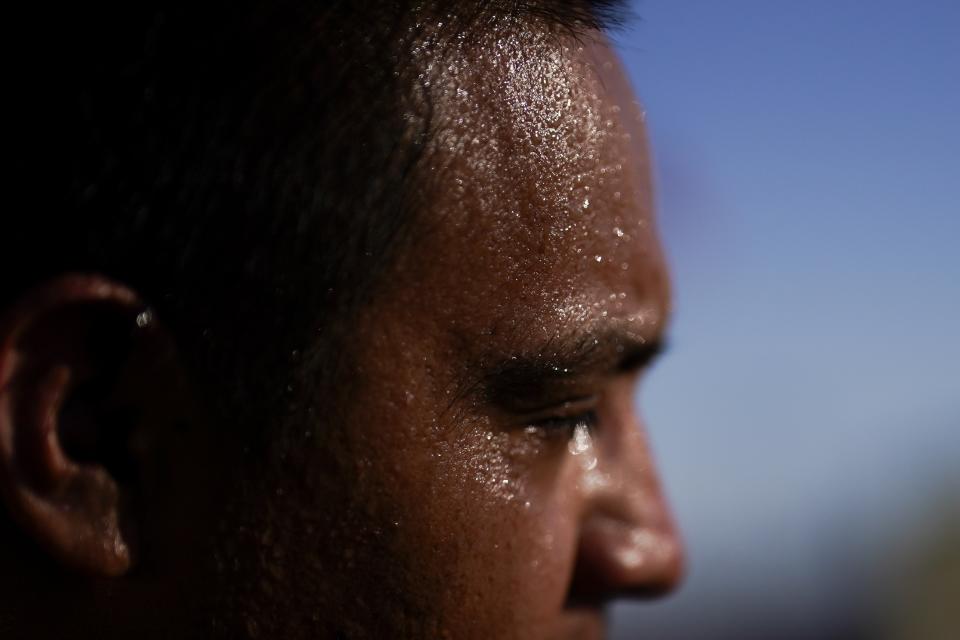 Sweat covers the face of Juan Carlos Biseno after dancing to music from his headphones as afternoon temperatures reach 115 degrees Fahrenheit (46.1 Celsius) Wednesday, July 19, 2023, in Calexico, Calif. (AP Photo/Gregory Bull)