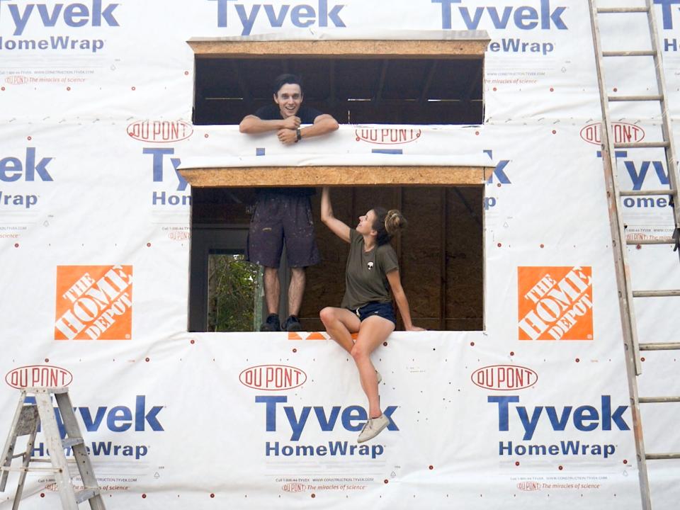 The tiny home owners sitting in the window spot of their under-construction tiny home