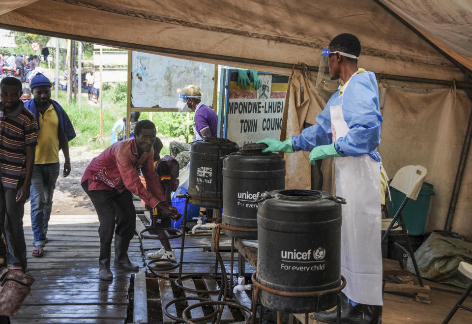 People coming from Congo wash their hands with chlorinated water to prevent the spread of infection, at the Mpondwe border crossing with Congo, in western Uganda Friday, June 14, 2019. In Uganda, health workers had long prepared in case the Ebola virus got past the screening conducted at border posts with Congo and earlier this week it did, when a family exposed to Ebola while visiting Congo returned home on an unguarded footpath. (AP Photo/Ronald Kabuubi)