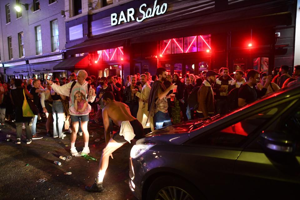 A car tries to drive along a street filled with revellers drinking in the Soho area of London on July 4, 2020, after the police re-opened the road at 2300 as restrictions are further eased during the novel coronavirus COVID-19 pandemic. - Pubs in England reopen on Saturday for the first time since late March, bringing cheer to drinkers and the industry but fears of public disorder and fresh coronavirus cases. (Photo by JUSTIN TALLIS / AFP) (Photo by JUSTIN TALLIS/AFP via Getty Images)