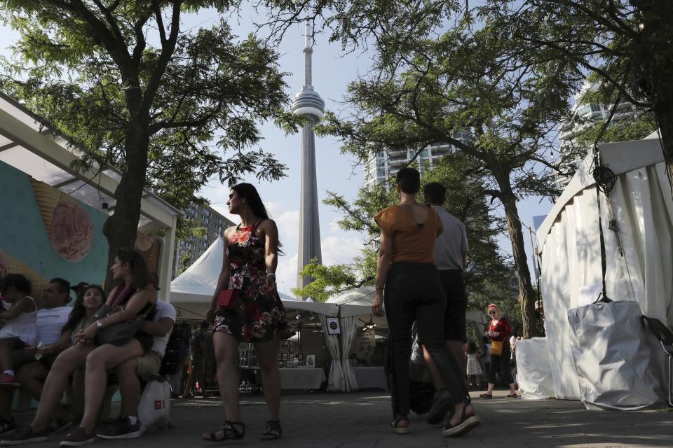 In this Saturday, July 27, 2019 photo, with CN Tower in the background, people visit the Lake View Market of Tirgan summer festival at the Harbourfront Centre in Toronto, Canada. The event aims to preserve and celebrate Iranian and Persian culture, said festival CEO Mehrdad Ariannejad. Among those who attended were second-and third-generation immigrants, many of whom have never been to Iran or have not been there since leaving the country following the 1979 Islamic Revolution. (AP Photo/Kamran Jebreili)