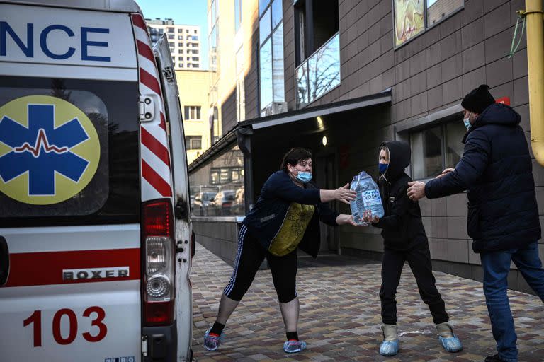 La gente descarga agua de una ambulancia en el hospital pediátrico de Kyin. 