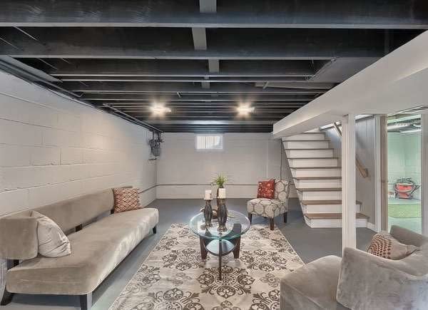 Finished basement with blue-gray painted rafters and cement block walls