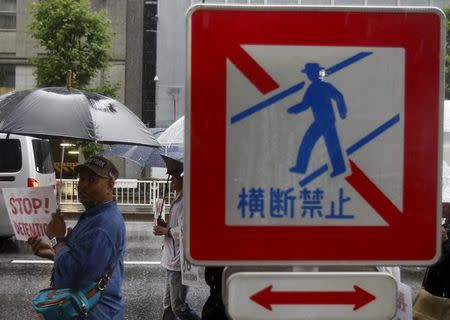 A protester holding a placard is seen at a "no crossing" traffic sign along a street during a rally to call for visa grants for asylum seekers in Japan, in central Tokyo, Japan, September 9, 2015. REUTERS/Yuya Shino