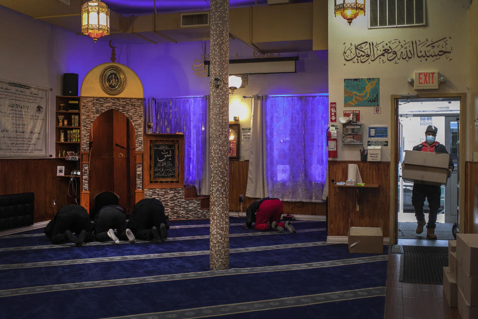 A volunteer carries food donations while other staff members and volunteers with Muslims Giving Back pray in the Muslim Community Center in the Bay Ridge neighborhood of Brooklyn in New York, on Monday, April 27, 2020. (AP Photo/Wong Maye-E)