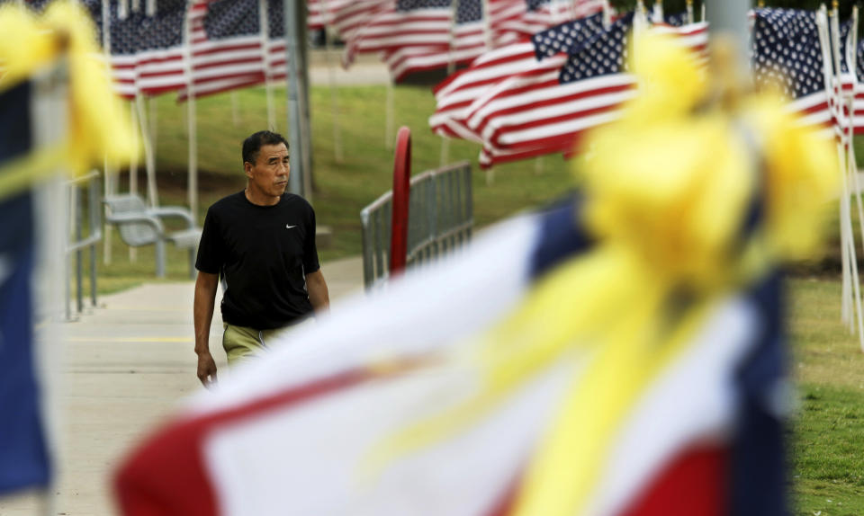 A man visits Memorial Gardens Park in Odessa, Texas, Monday, Sept. 9, 2019, walking by the seven Texas flags that represent the seven killed in a recent shooting in the Odessa and Midland area. (Ben Powell/Odessa American via AP)