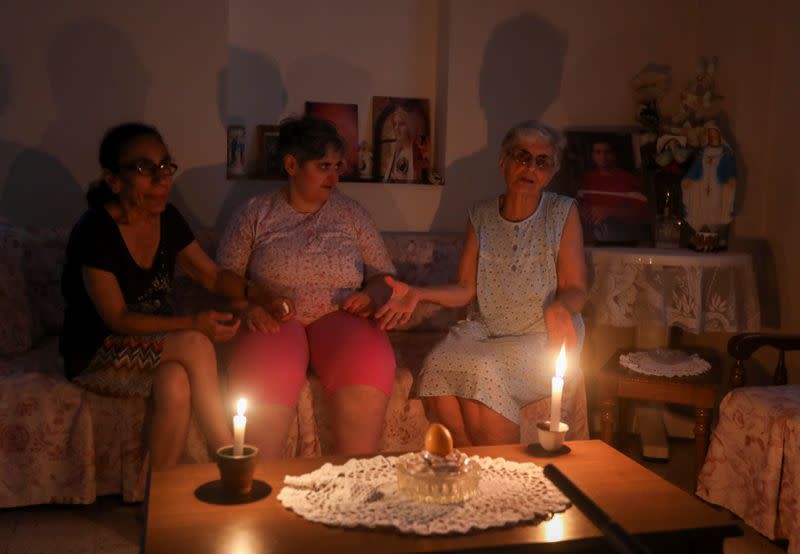 Samira Hanna, 70, lights candles to light up the room during a power cut in Beirut