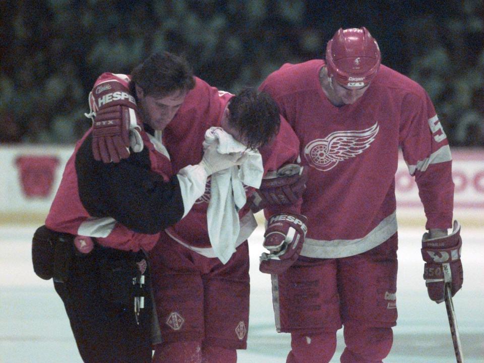 Red Wings forward Kris Draper, center, is helped off the ice by trainer John Wharton, left, teammate Keith Primeau after Draper was hit into the boards from behind by Avalanche forward Claude Lemieux during Game 6 of the Western Conference finals on May 29, 1996, in Denver.