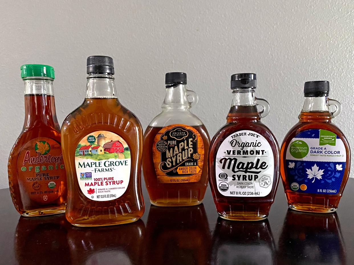 five brands of maple syrup on a row on a kitchen table