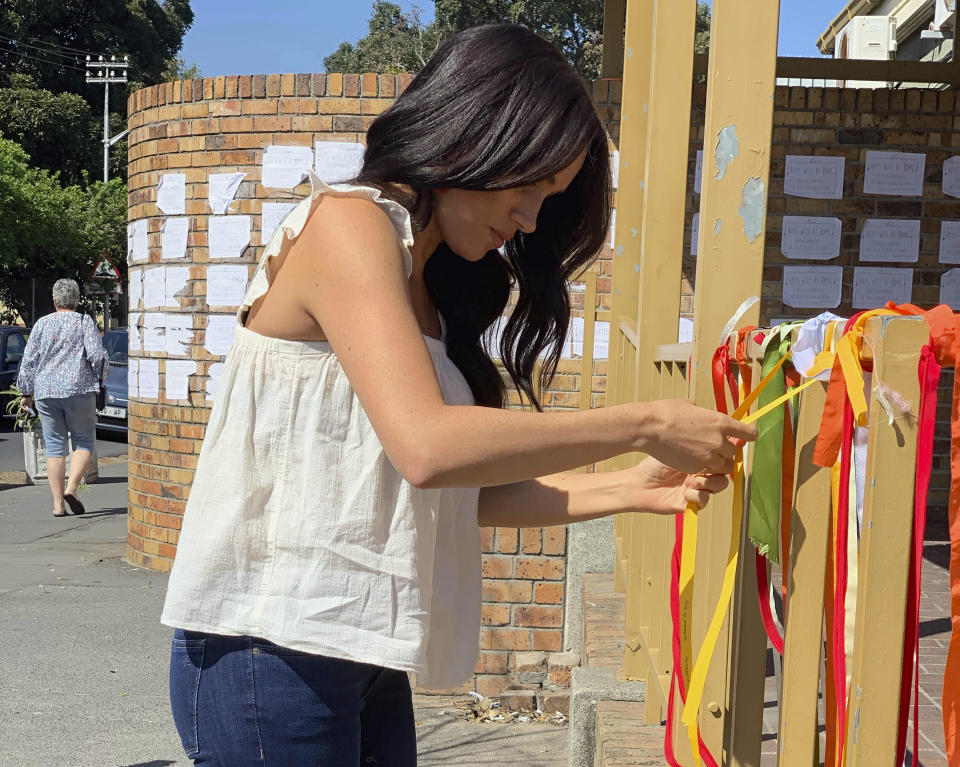 Photo by: KGC-178/STAR MAX/IPx 2019 9/28/19 Meghan, The Duchess of Sussex, ties a ribbon at the memorial to student Uyinene Mrwetyana at the post office where she was raped and murdered last month. A post on the official Instagram account of the Duke and Duchess of Sussex said "The Duke and Duchess had been following what had happened from afar and were both eager to learn more when they arrived in South Africa." These images were posted on @SussexRoyal today and supplied by the Royal Household.